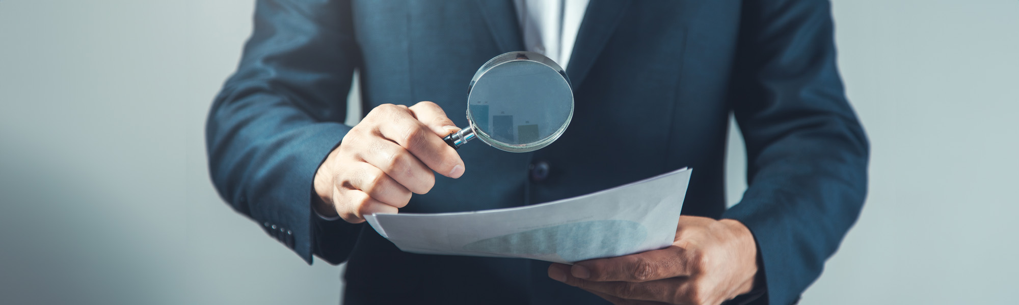 man looking at documents with magnifying glass image